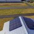 Dual solar panel array next to airport on a metal roof.